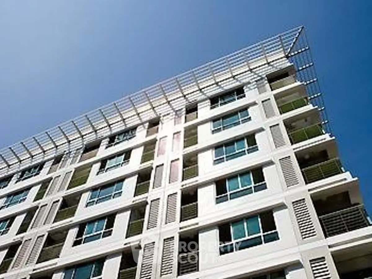 Modern apartment building with sleek design and large windows under a clear blue sky.