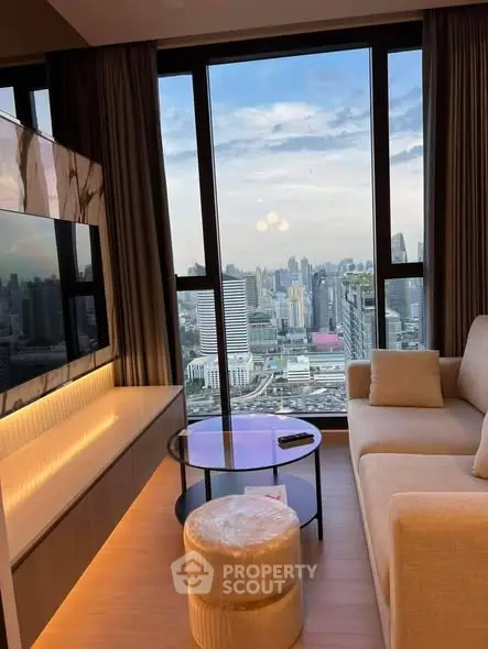 Luxurious living room with stunning city view from high-rise apartment, featuring modern furniture and floor-to-ceiling windows.