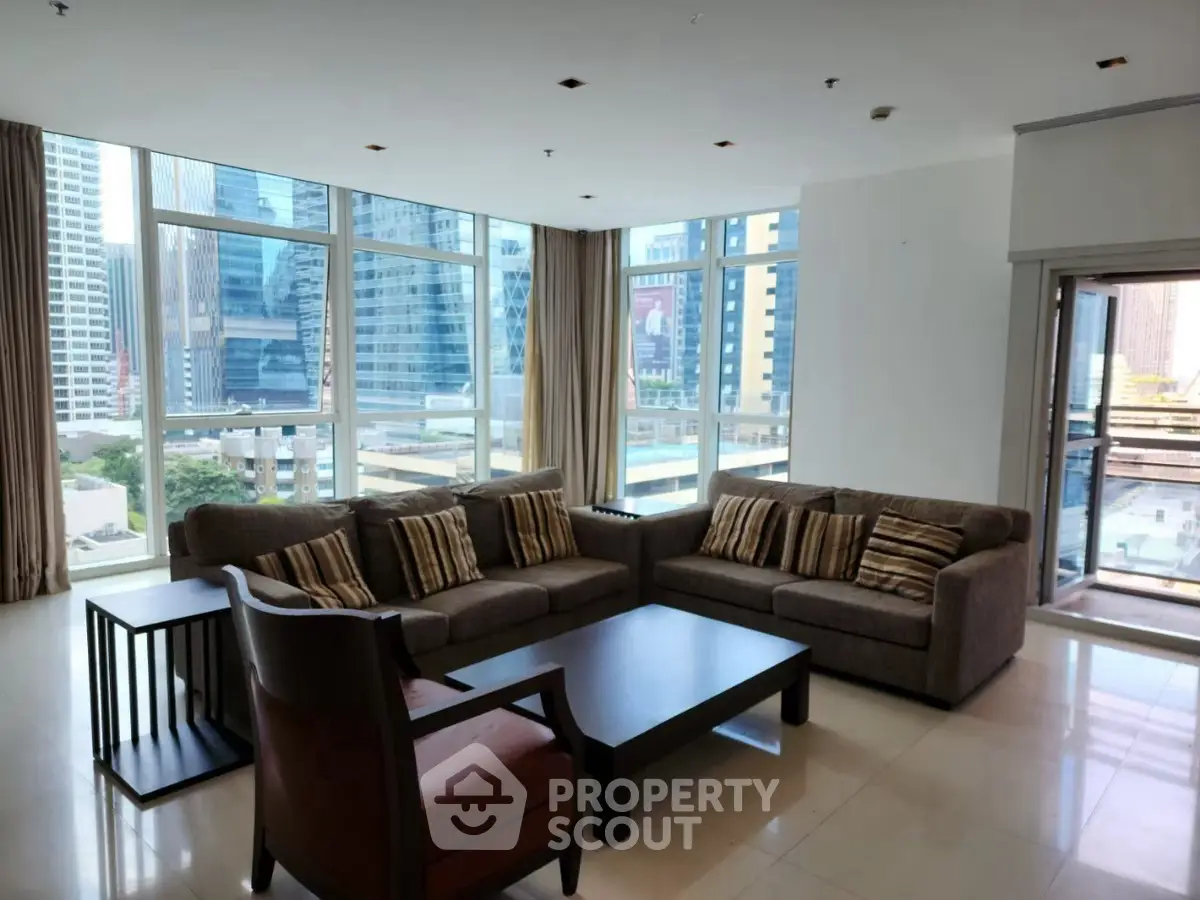 Spacious living room with modern furniture and city view through large windows.