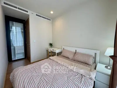 Cozy bedroom with modern decor and natural light, featuring a comfortable bed and a small study area.