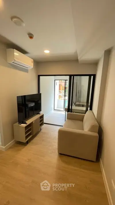 Modern living room with sleek design, featuring a cozy sofa, flat-screen TV, and access to a balcony.