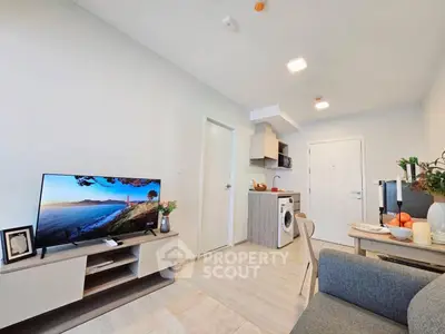 Modern living room with open kitchen and washing machine, stylish decor and natural light.