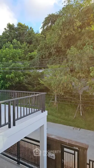 Modern balcony with lush green garden view and sleek railing design.