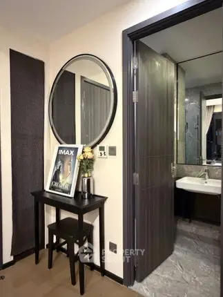 Stylish entryway with round mirror and view into modern bathroom