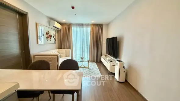 Modern living room with stylish decor and large TV, featuring a cozy seating area and natural light.