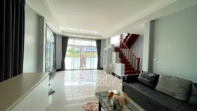 Spacious modern living room with large windows and elegant staircase