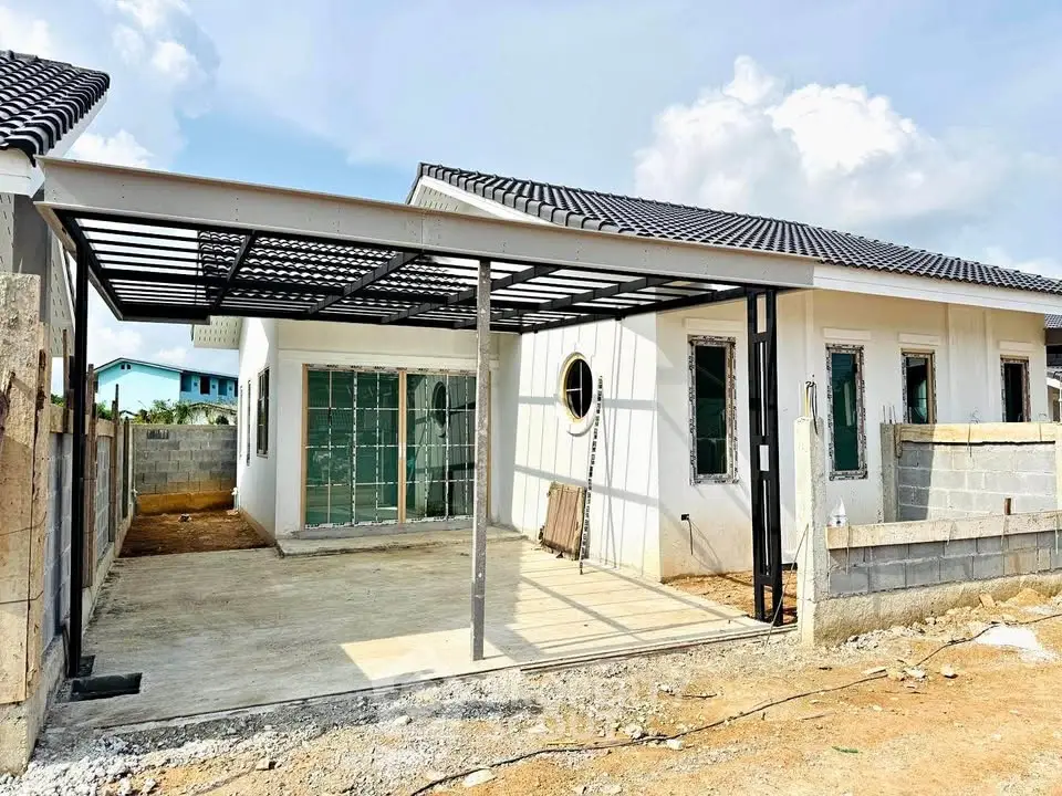 Modern single-story house under construction with carport and large windows