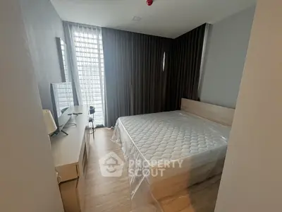 Modern bedroom with large window and stylish furnishings in a contemporary apartment.