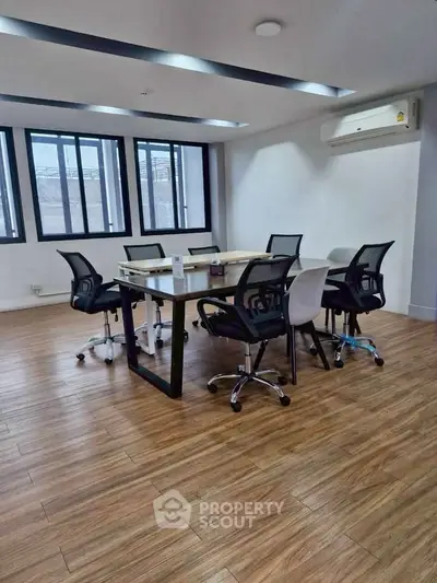 Modern office space with sleek wooden flooring and ergonomic chairs around a conference table.
