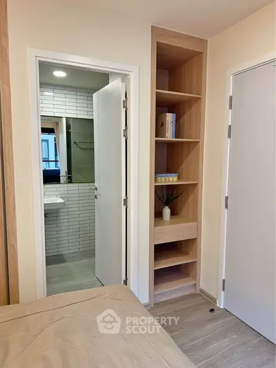Modern bedroom with built-in shelves and en-suite bathroom featuring sleek design.