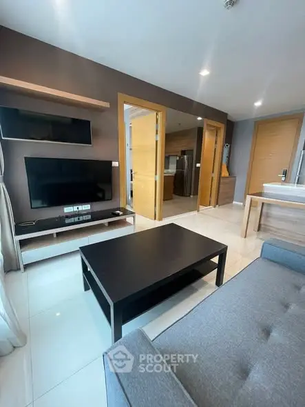 Modern living room with sleek furniture and open layout, featuring a flat-screen TV and stylish decor.