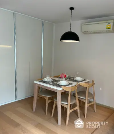 Modern dining area with sleek table and chairs, featuring minimalist design and air conditioning.