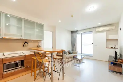 Modern open-plan living room with kitchen, featuring sleek furniture and natural light.