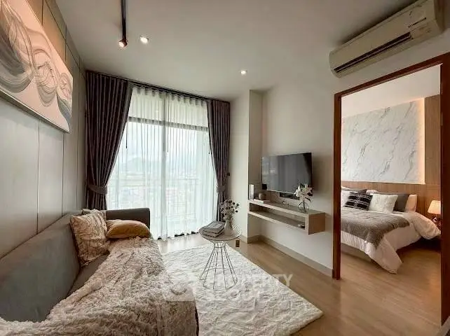 Modern living room with cozy decor and bedroom view, featuring elegant furnishings and natural light.