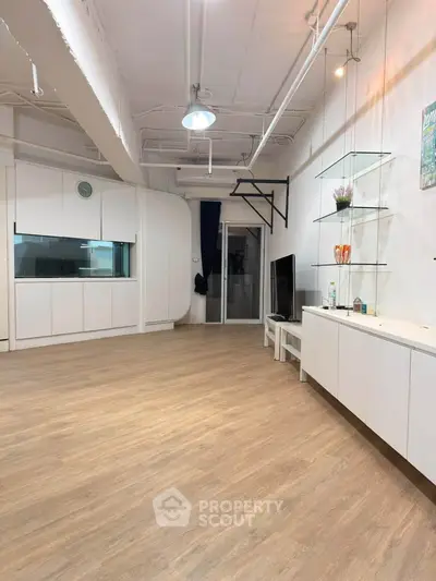 Spacious modern living room with sleek wooden flooring and stylish built-in storage.