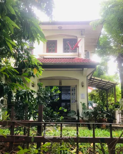 Charming two-story house with lush garden and inviting entrance.