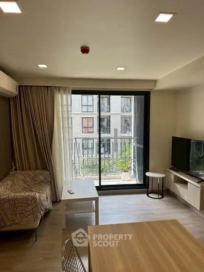 Modern living room with balcony view, featuring sleek furniture and natural light.