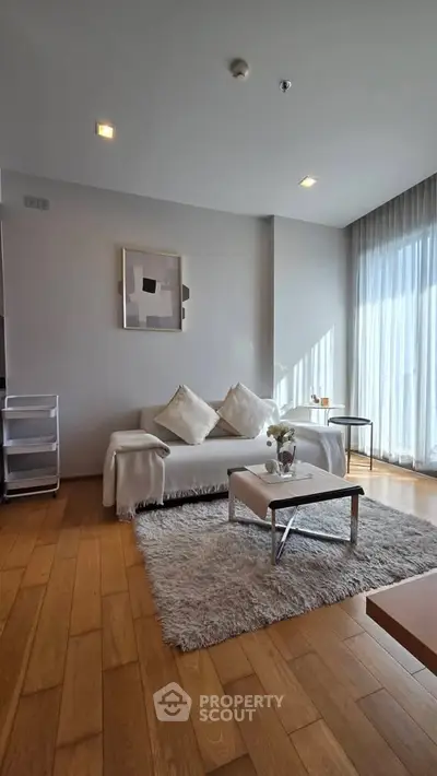 Modern living room with cozy decor and natural light, featuring a plush rug and stylish furniture.