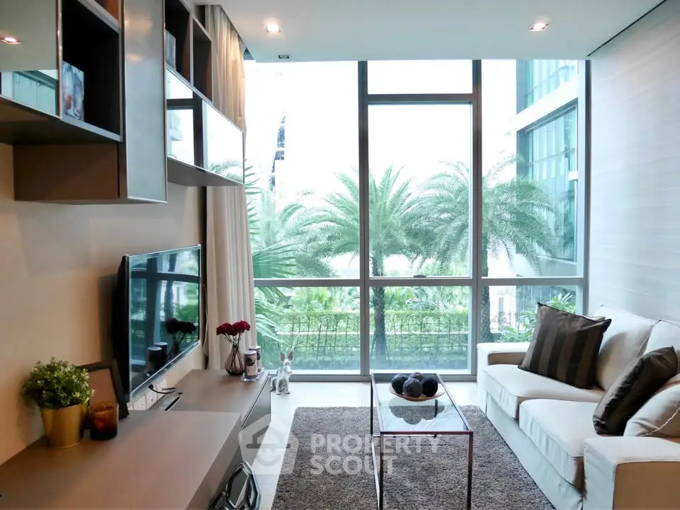 Modern living room with large windows and stylish decor overlooking lush greenery.