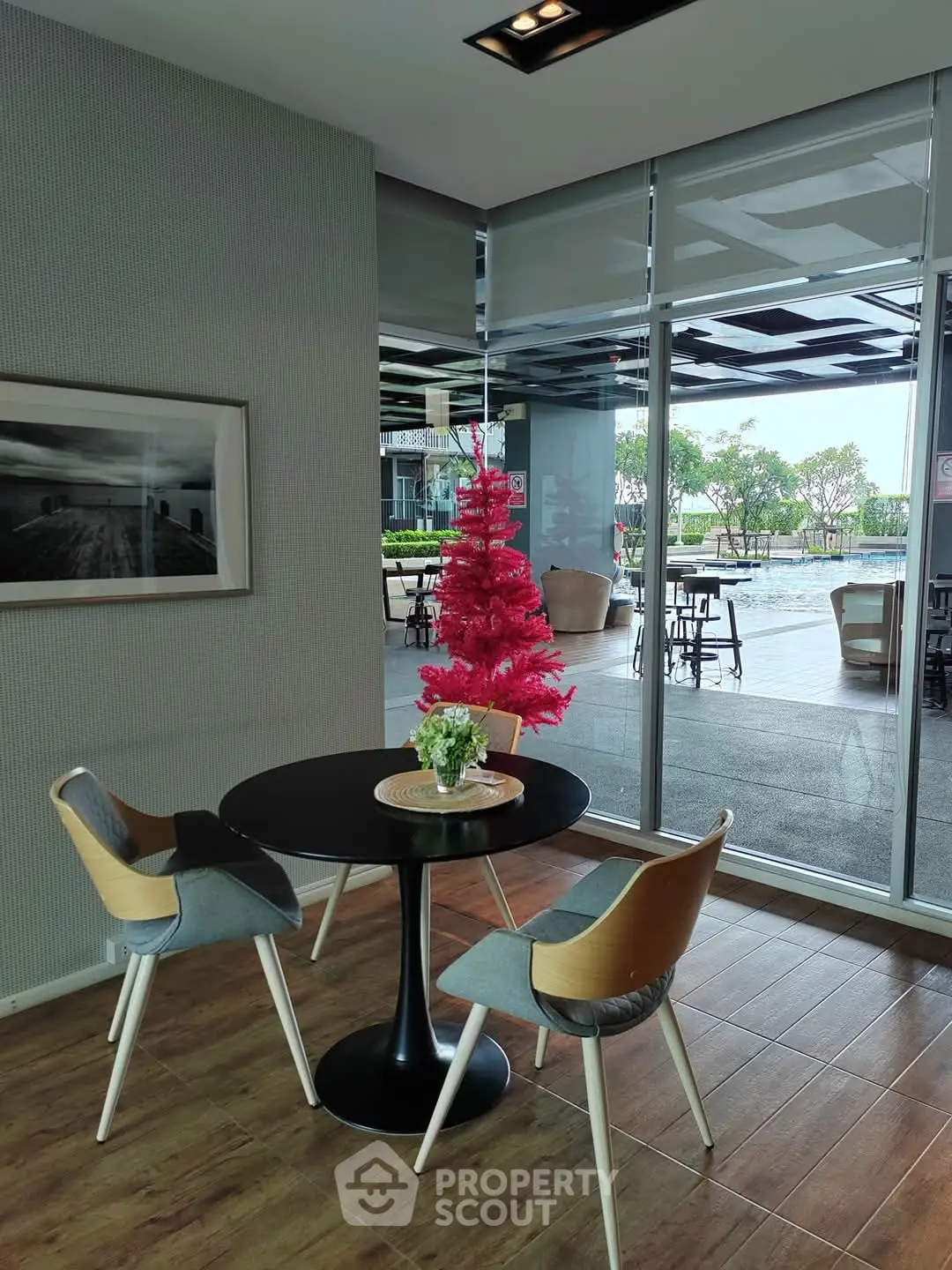 Modern dining area with stylish chairs and table, overlooking a pool through large glass windows.