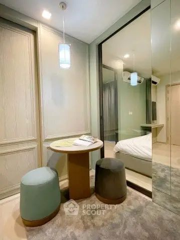 Cozy modern bedroom with stylish seating area and mirrored closet doors.
