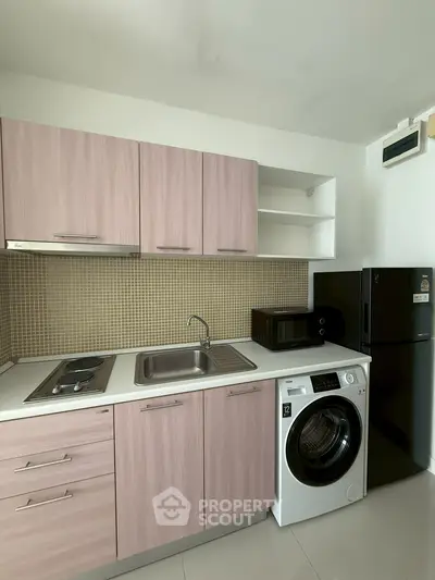 Modern kitchen with sleek cabinetry, washing machine, and appliances in compact layout.