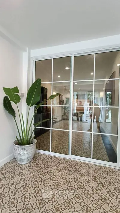 Stylish interior with large mirror doors and decorative plant in modern living space.