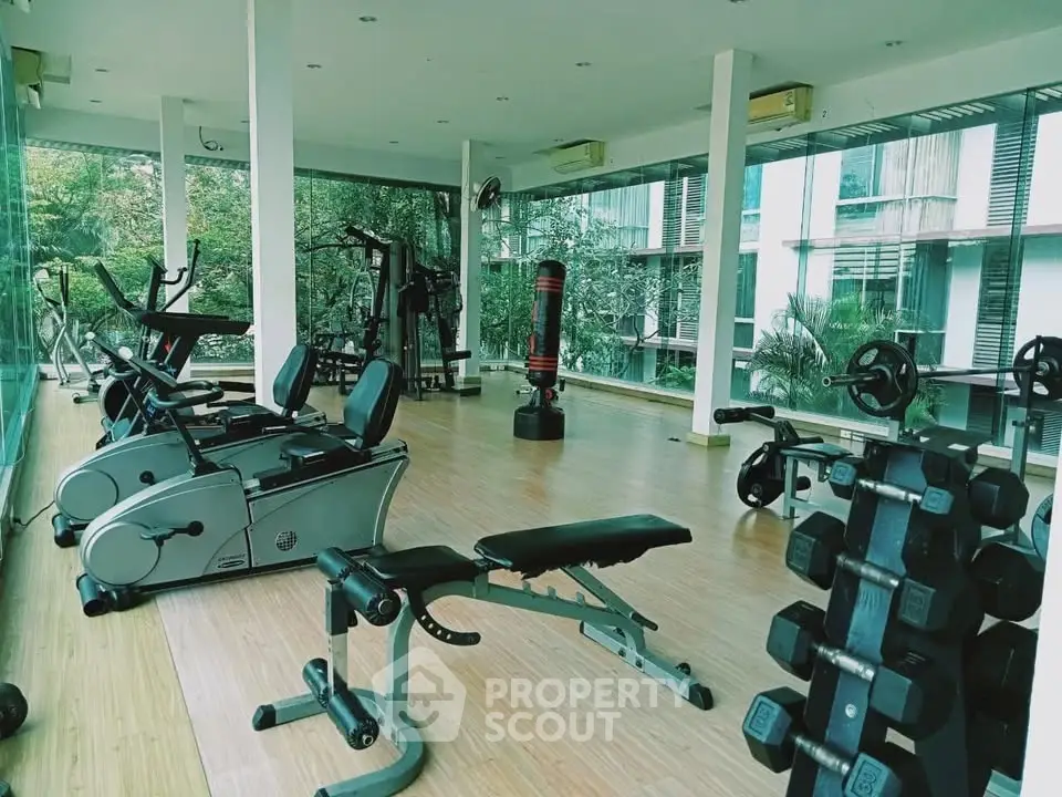 Spacious gym with modern equipment and large windows offering a serene view, perfect for fitness enthusiasts.