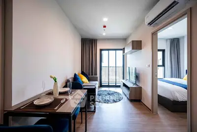 Modern open-plan living room with dining area and bedroom in a stylish apartment.