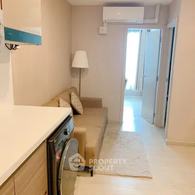Cozy living room with modern sofa and washing machine in compact apartment.