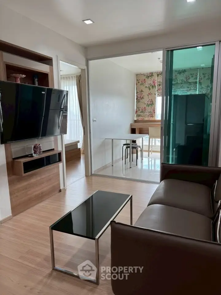 Modern living room with sleek furniture and open layout leading to dining area.