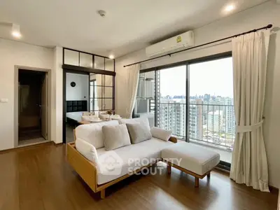 Modern living room with city view, featuring stylish furniture and large windows for natural light.
