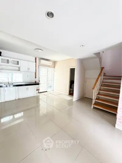 Spacious open-plan living area with modern kitchen and staircase, perfect for family gatherings.
