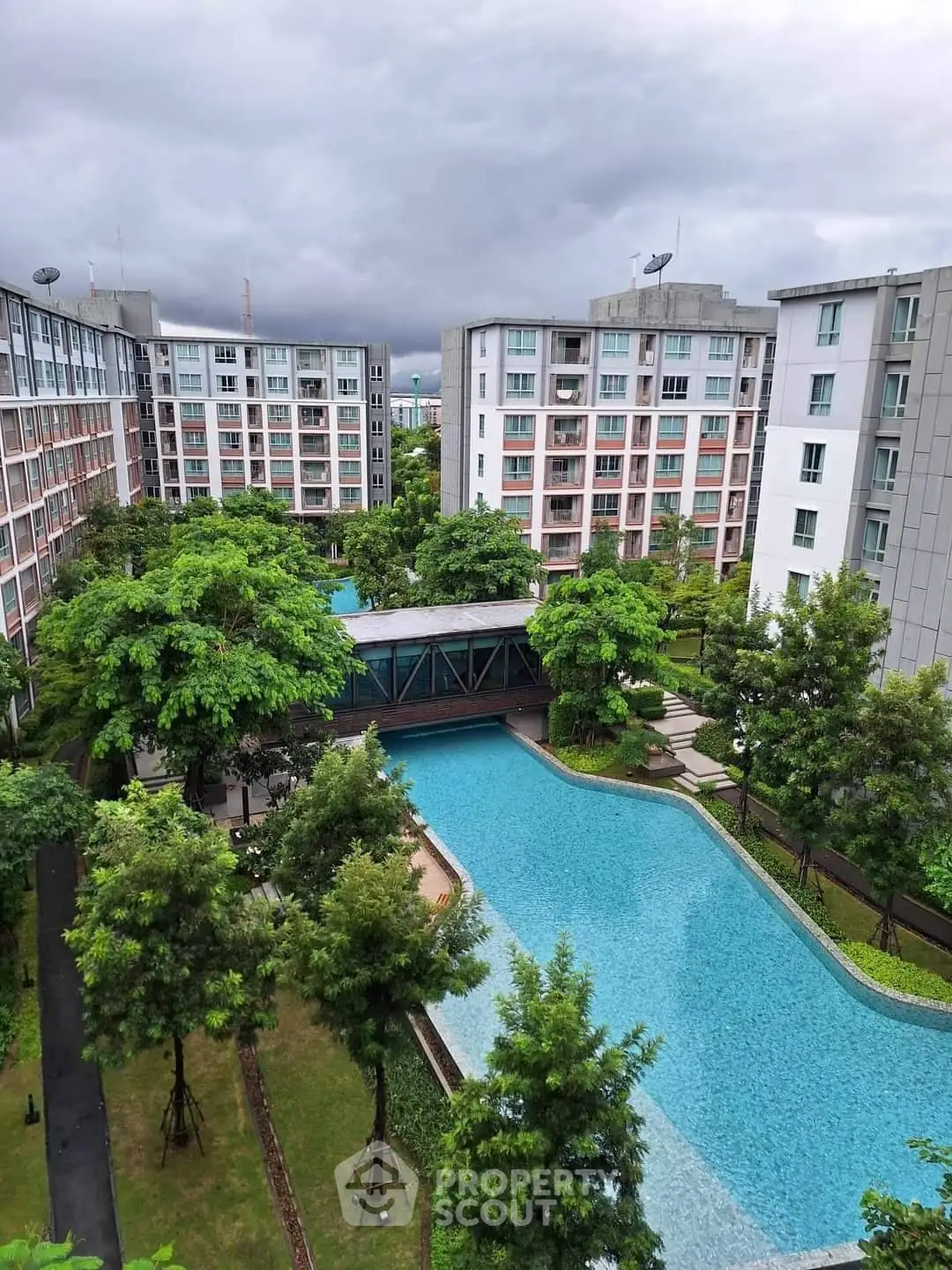 Luxurious residential complex with stunning pool and lush greenery, offering serene urban living.