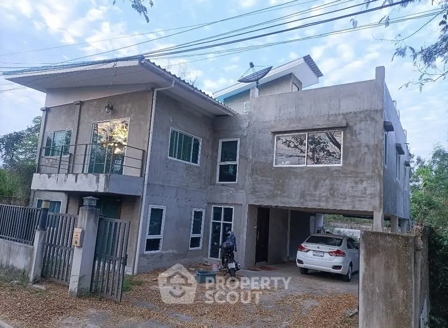 Modern concrete house with large windows and carport in a serene neighborhood.