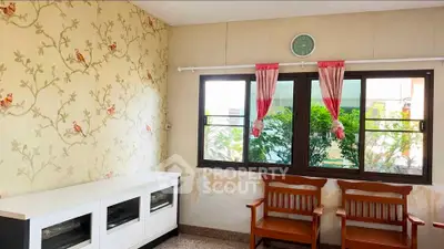 Charming living room with vintage wallpaper and wooden chairs, offering a cozy ambiance and natural light.