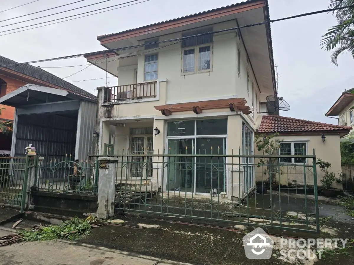 Charming two-story house with gated entrance and tiled roof in suburban neighborhood