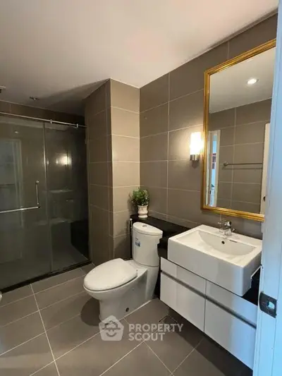 Modern bathroom with sleek fixtures and glass shower enclosure in a contemporary home.