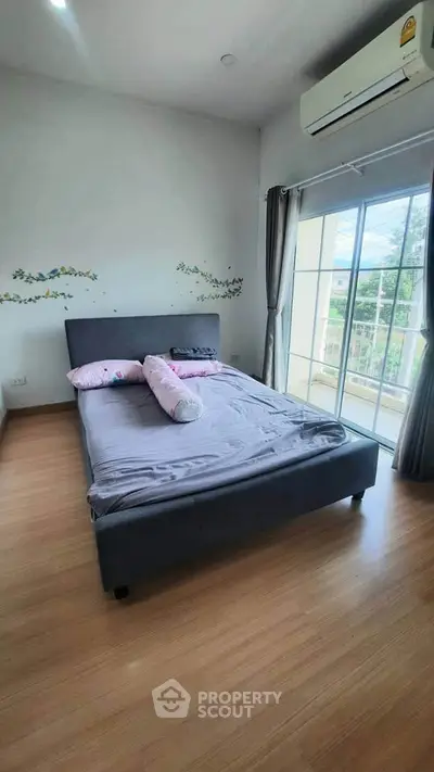 Cozy bedroom with large window and air conditioning, perfect for relaxation.