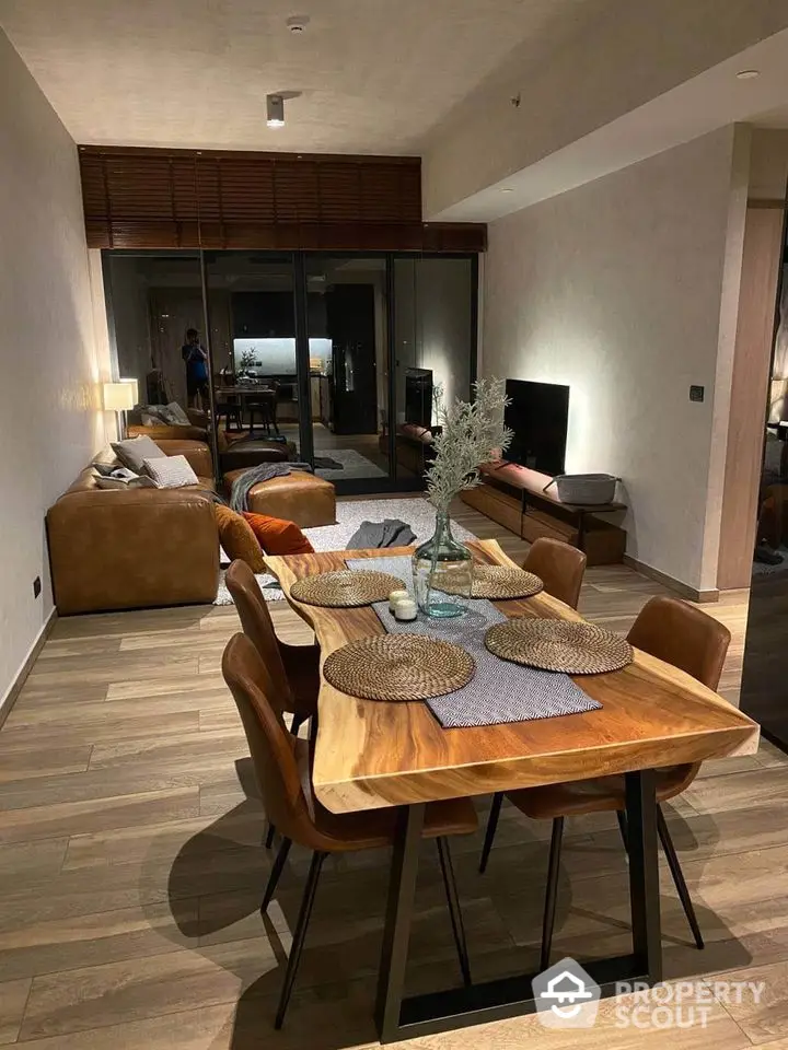 Modern open-plan living room with stylish dining area and cozy seating, featuring wooden flooring and contemporary decor.