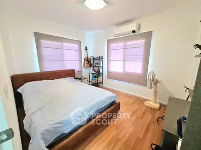 Cozy bedroom with wooden flooring, modern decor, and ample natural light.