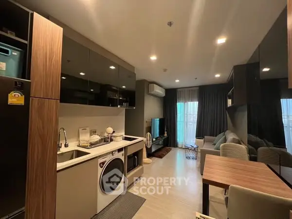 Modern open-plan living room with kitchen, featuring sleek appliances and cozy seating area.