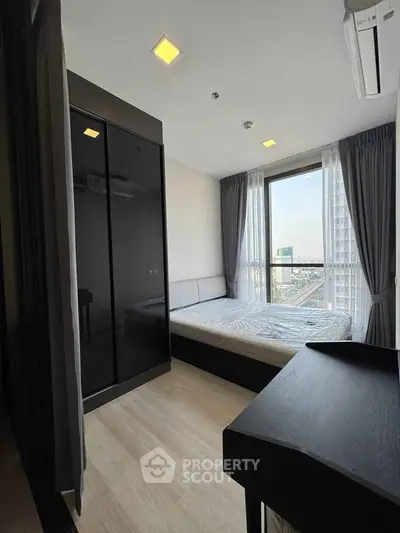 Modern bedroom with city view, featuring sleek black wardrobe and large window for natural light.