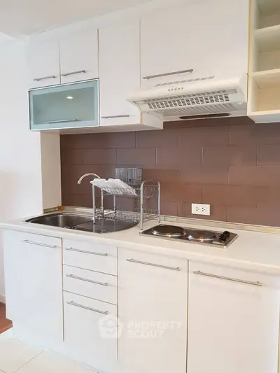Modern compact kitchen with sleek white cabinetry and stainless steel appliances.