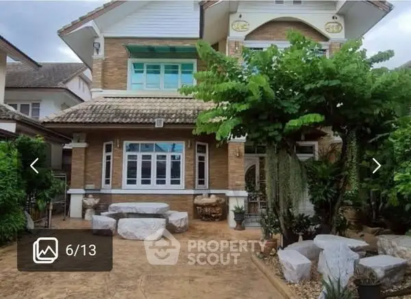 Charming two-story house with lush garden and stone seating area