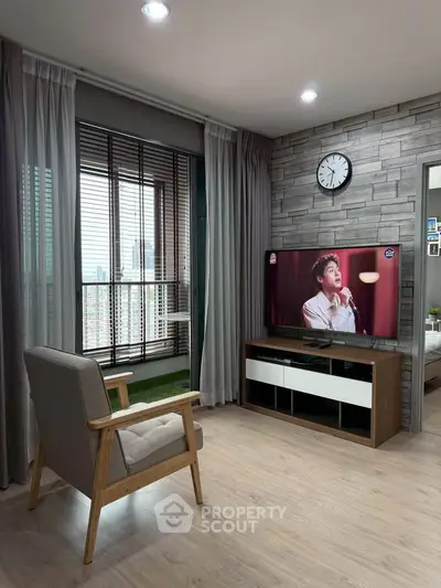 Modern living room with stylish decor, featuring a TV, armchair, and large window with city view.