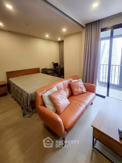 Modern bedroom with cozy seating and balcony view in urban apartment