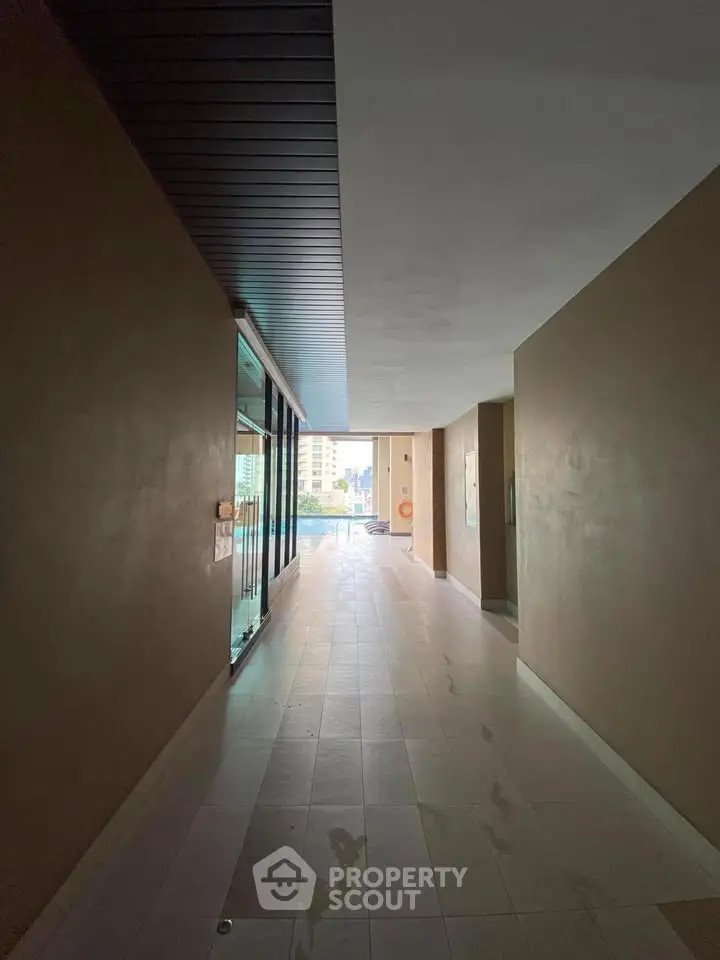Spacious corridor leading to a pool area with city views, perfect for relaxation and leisure.