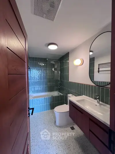 Modern bathroom with green tiles, bathtub, and stylish vanity