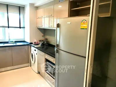 Modern kitchen with sleek cabinets, stainless steel fridge, and washing machine